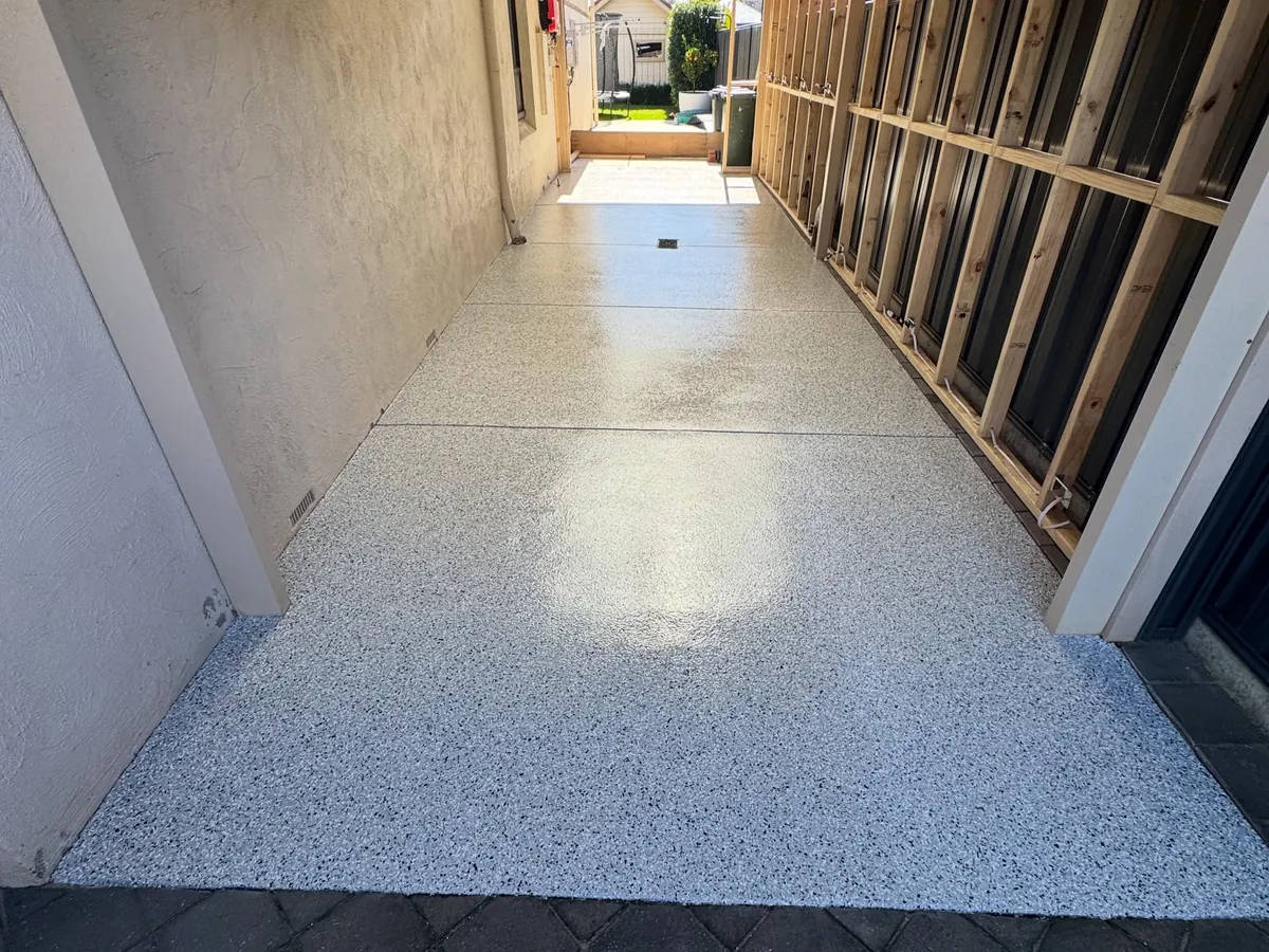 Side carport after coating — light grey flake floor with a gloss finish running the length of the house