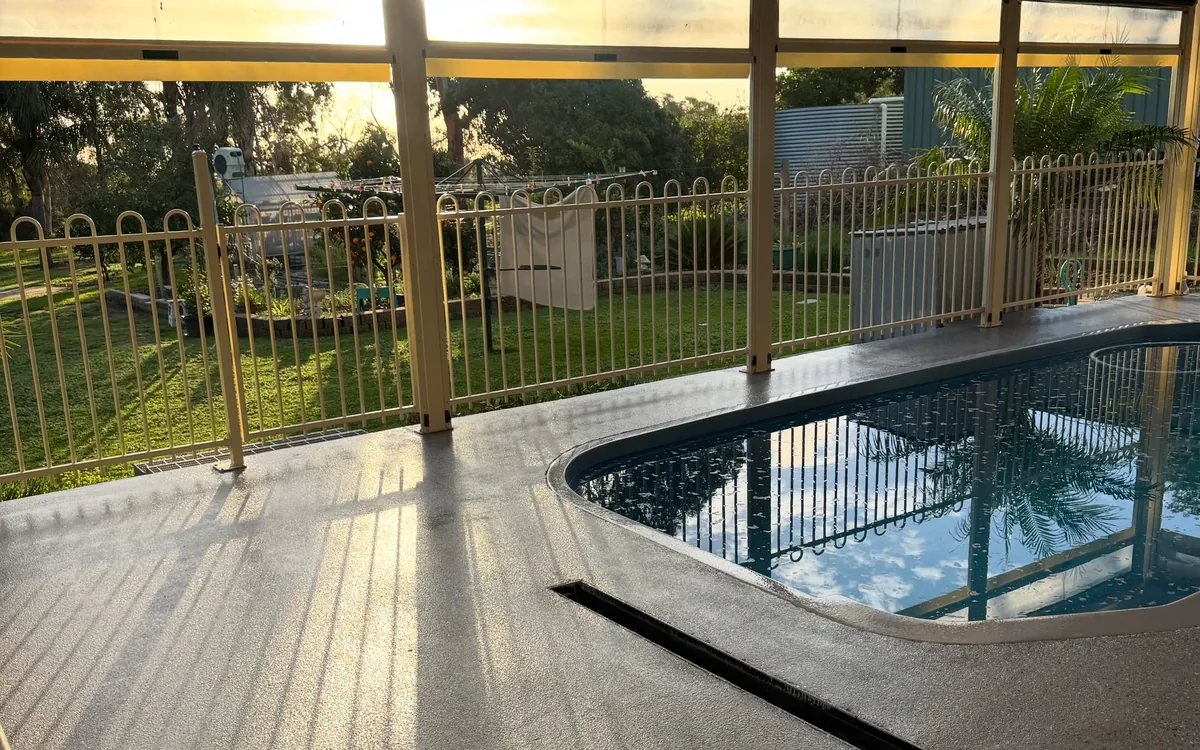Covered pool enclosure at sunset with a flake-coated floor running to the edge of the pool